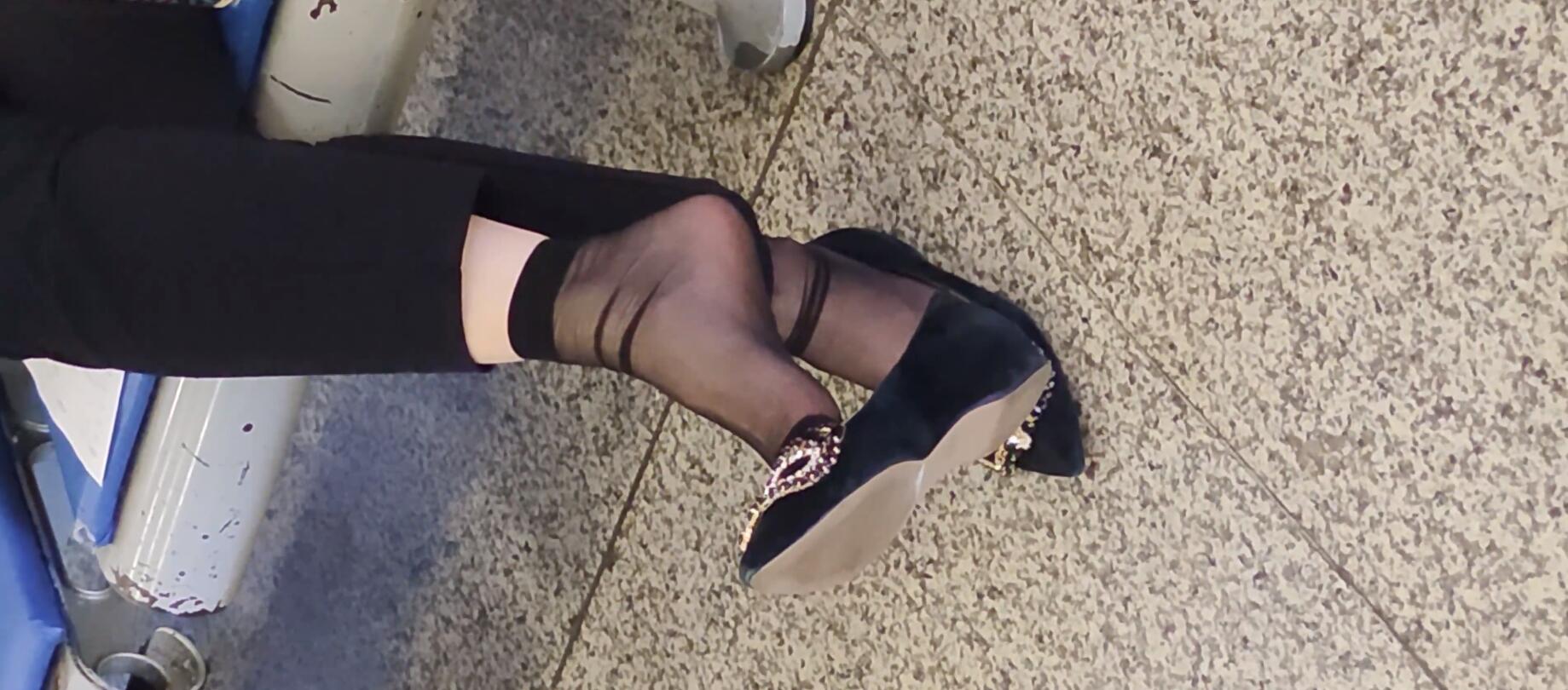 The middle-age lady in black nylon dangling shoeplay  when waiting for a train 