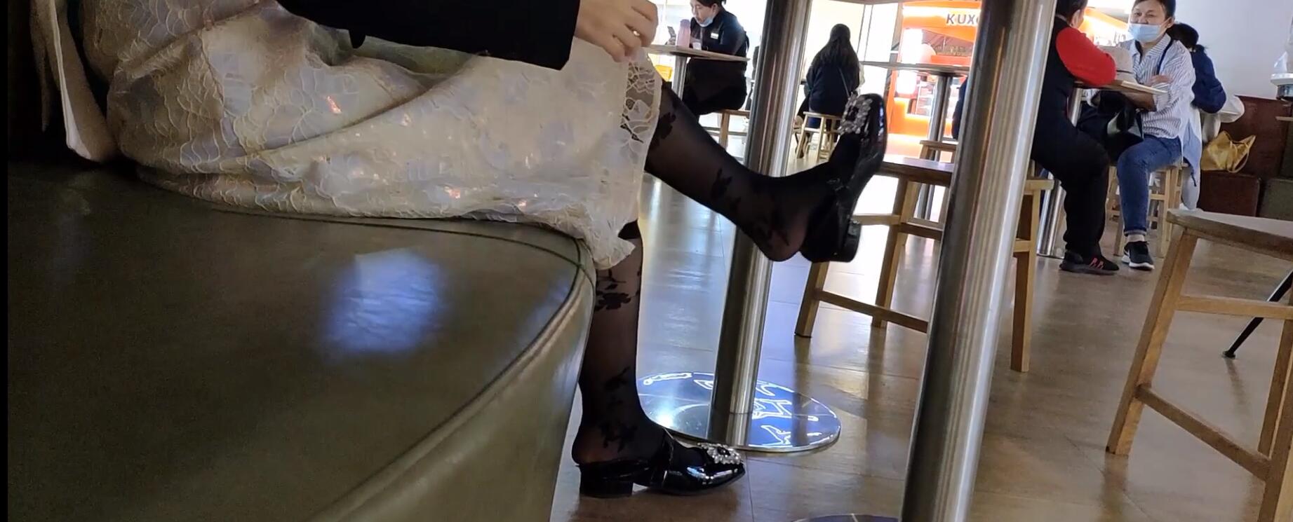 The hot girl in black nylon dangling shoeplay under the table  when having lunch 