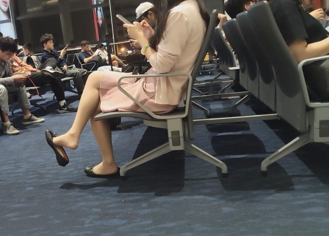 The lady dangling shoeplay when waiting for the plane