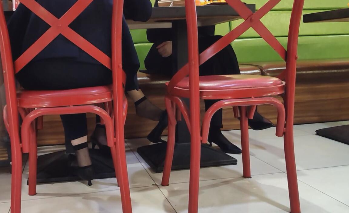 The hostess in black nylon dangling shoeplay under the table when having lunch