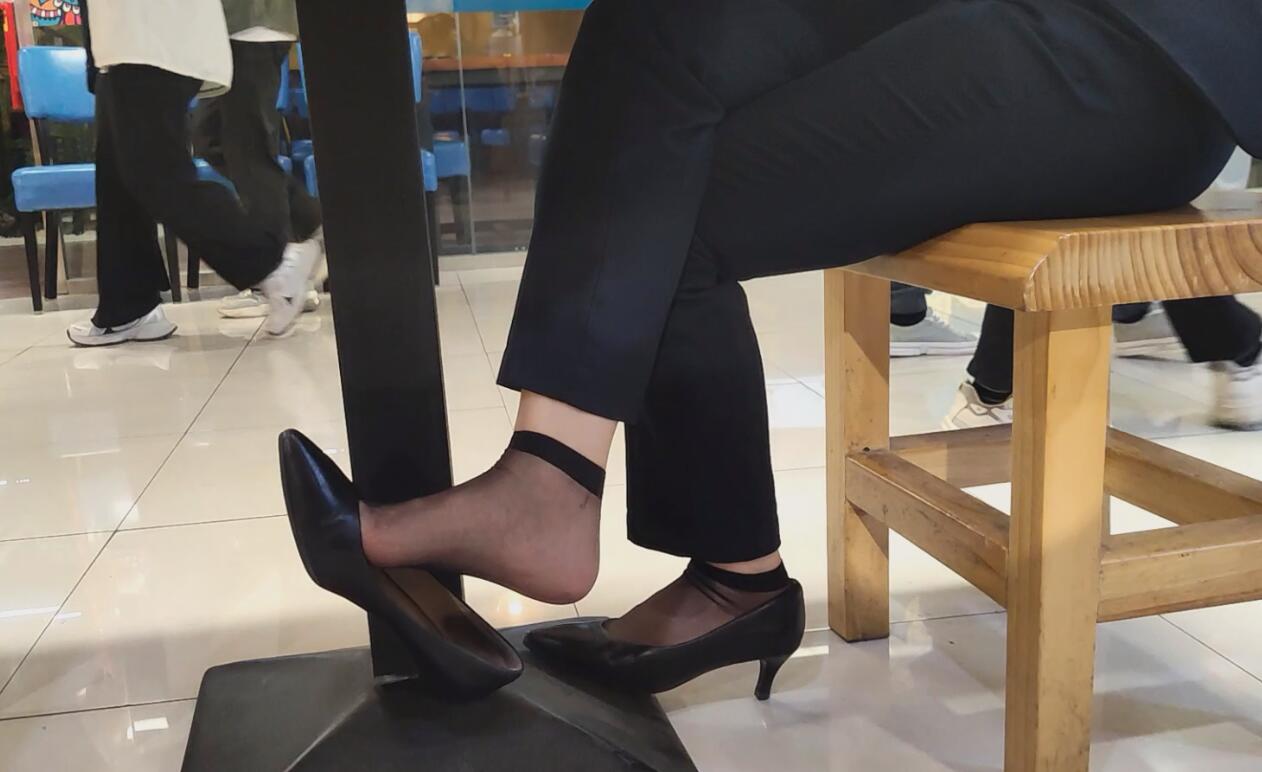 The hostess in black nylon great dangling shoeplay under the table when having lunch